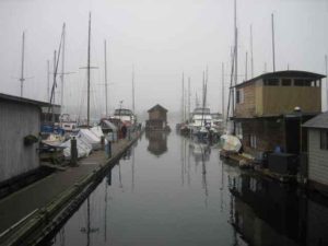 A marina with boats and houseboats, with one houseboat being moved out along the fairway